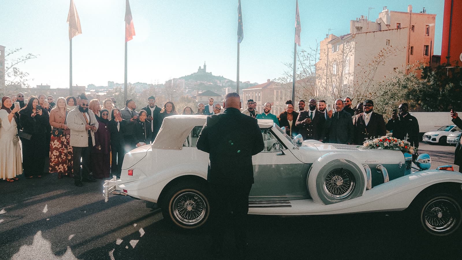 Les invités autour de la voiture ancienne, Notre-Dame de la Garde au loin