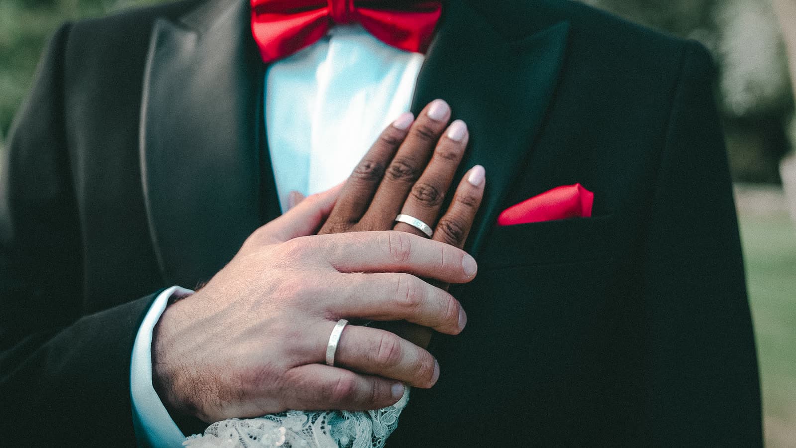 La main de la mariée sur la veste du marié, les alliances au doigt