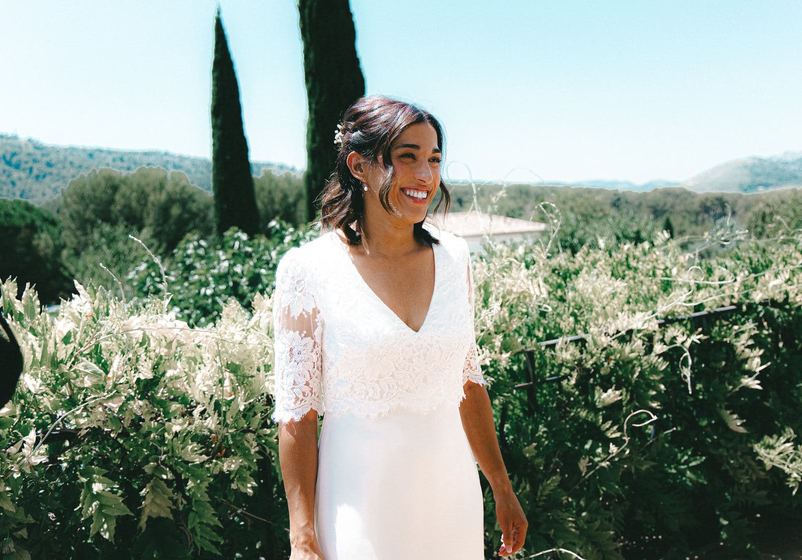La mariée dans le jardin en plein soleil, les cyprès derrière elle