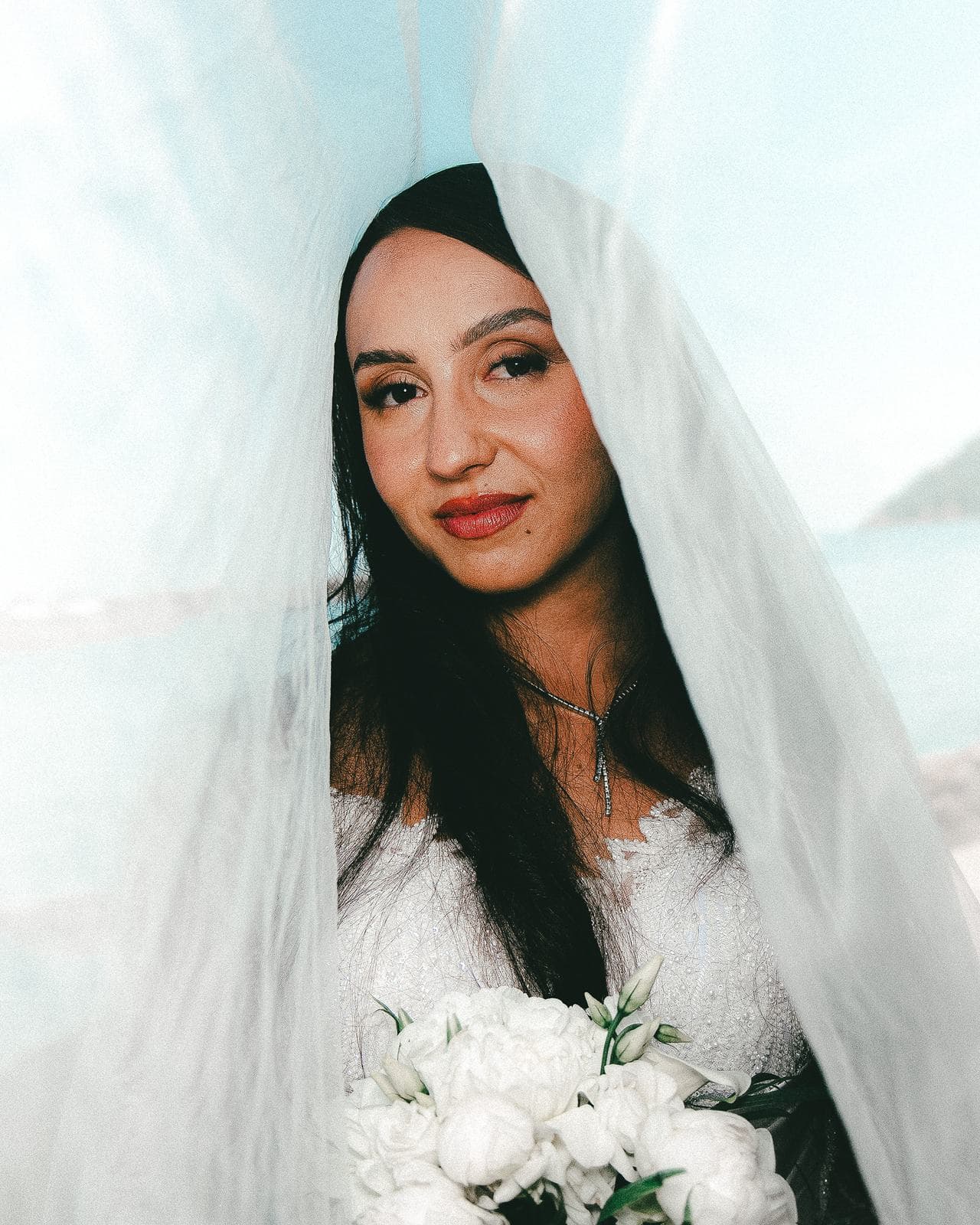 Portrait de la mariée sous son voile, la mer derrière elle