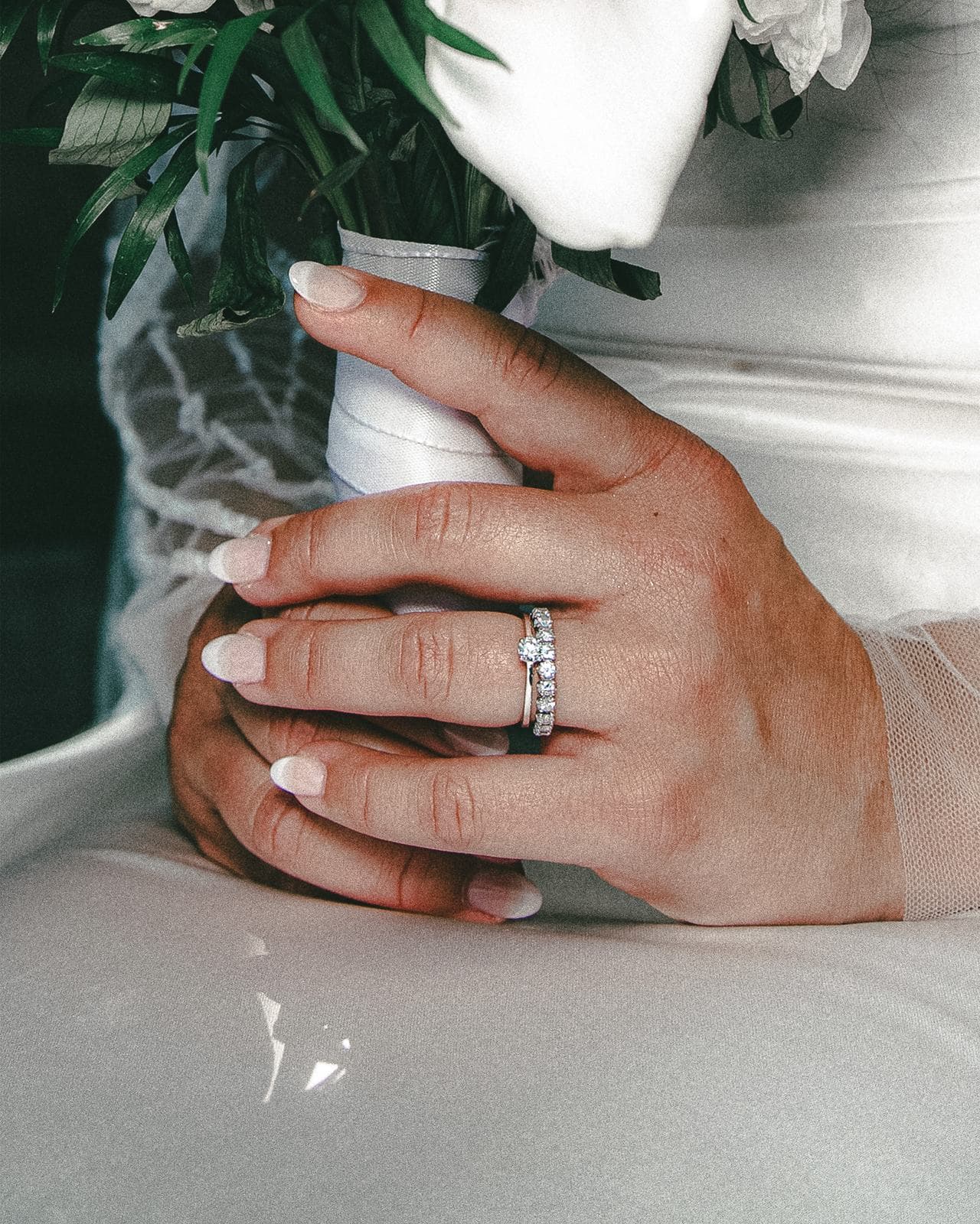 La main de la mariée, l’alliance au doigt, posée sur le bouquet